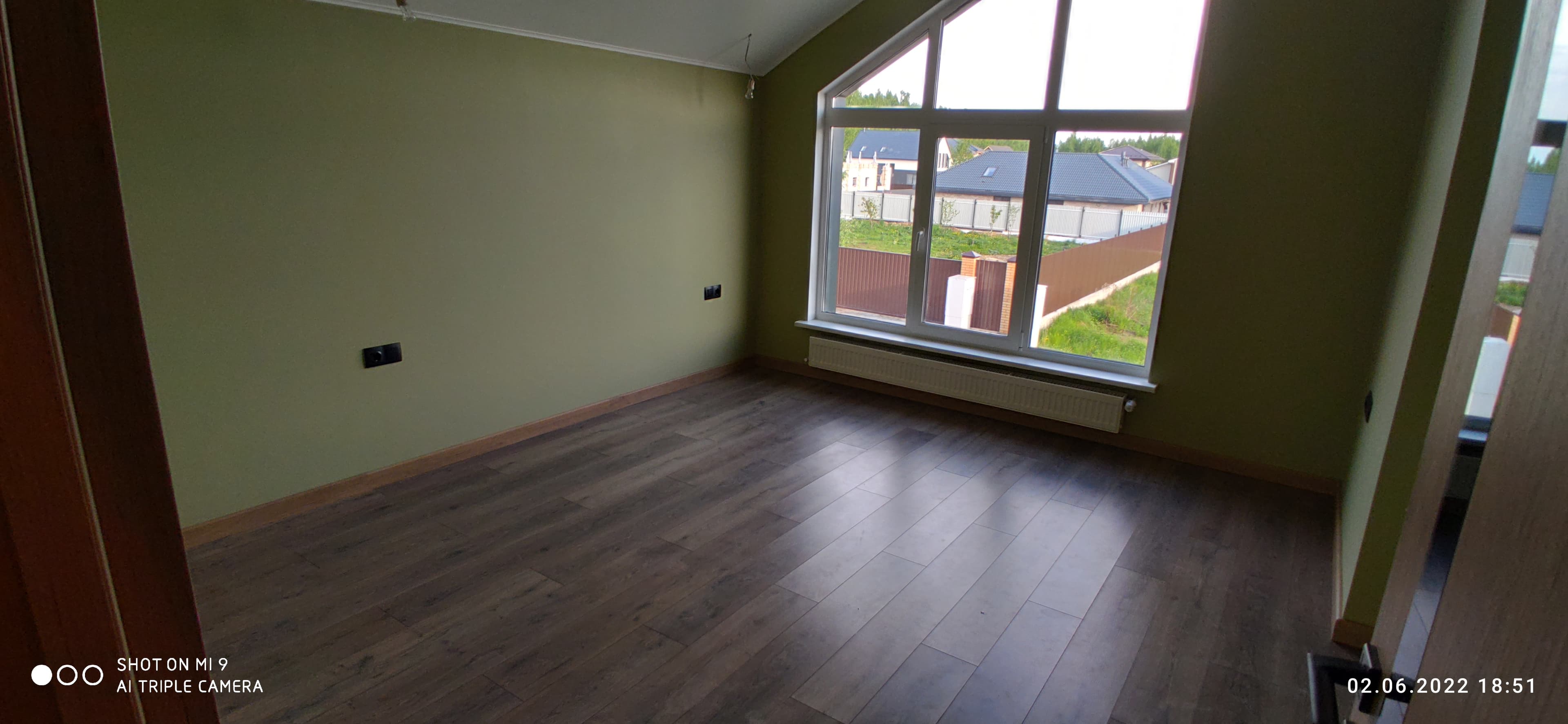 Спальня с большим окном и деревянным полом